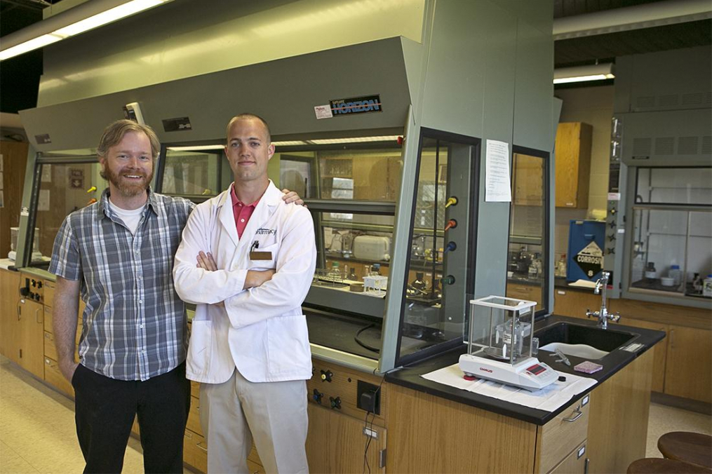 A professor and alumni stand next to one another.