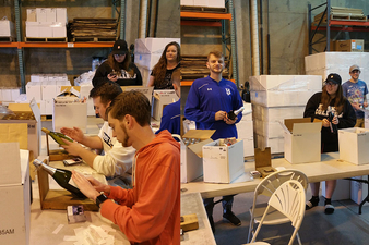 Students taking the popular BUS-410 Entrepreneurship class hand-place custom Keuka College labels on wine bottles they sold as part of the class. Some of the proceeds will fund scholarships for returning juniors and seniors who need a small financial boost to be able to stay at Keuka College.